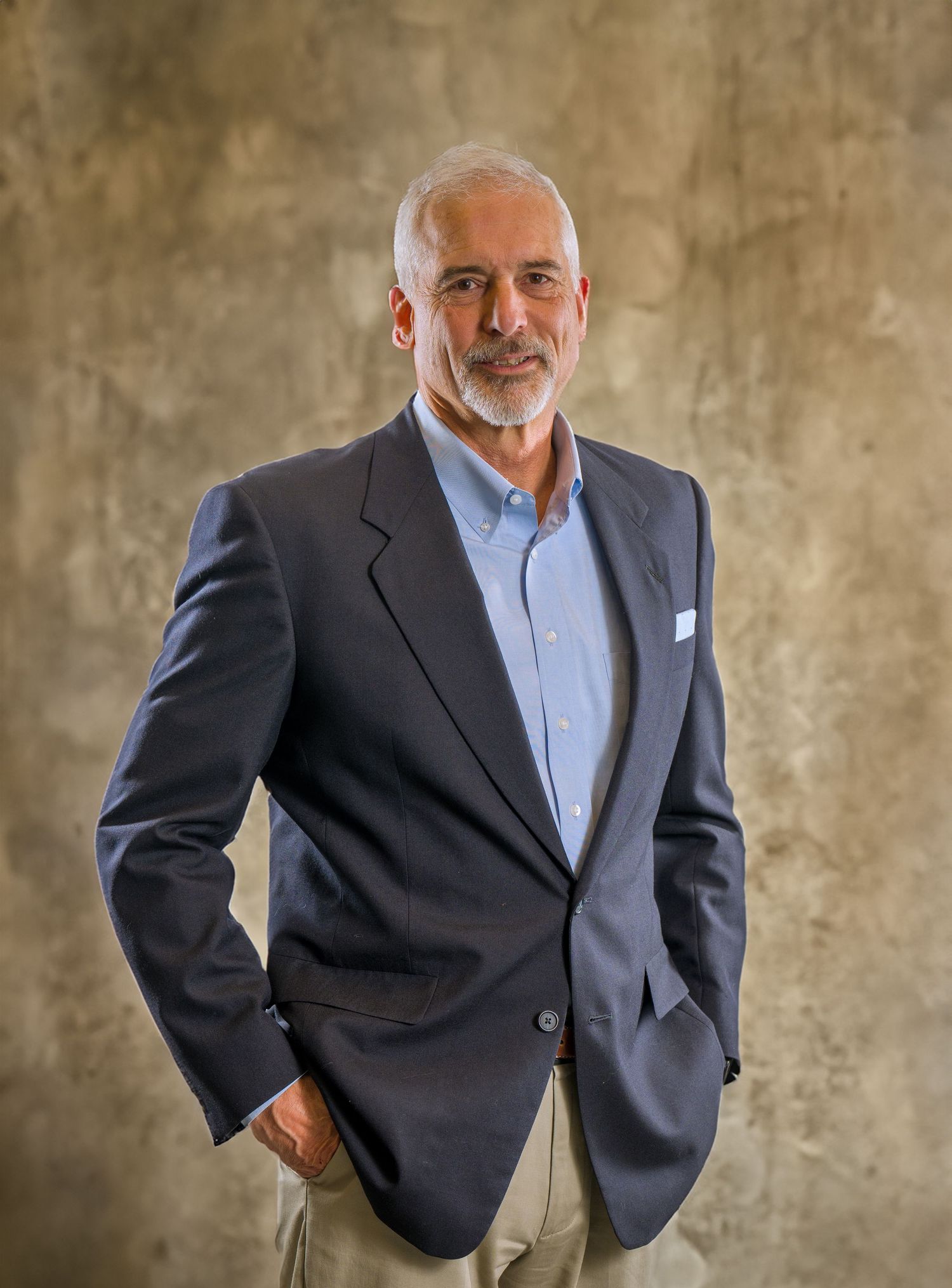 Executive portrait series against textured beige wall showcasing formal business attire.