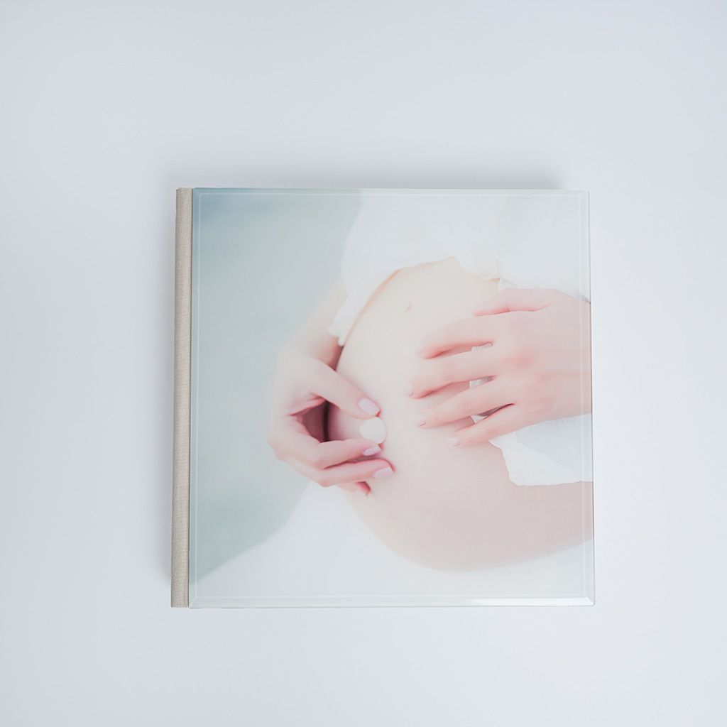 Square art book cover featuring soft pastel tones with two hands gently holding a smooth round object.