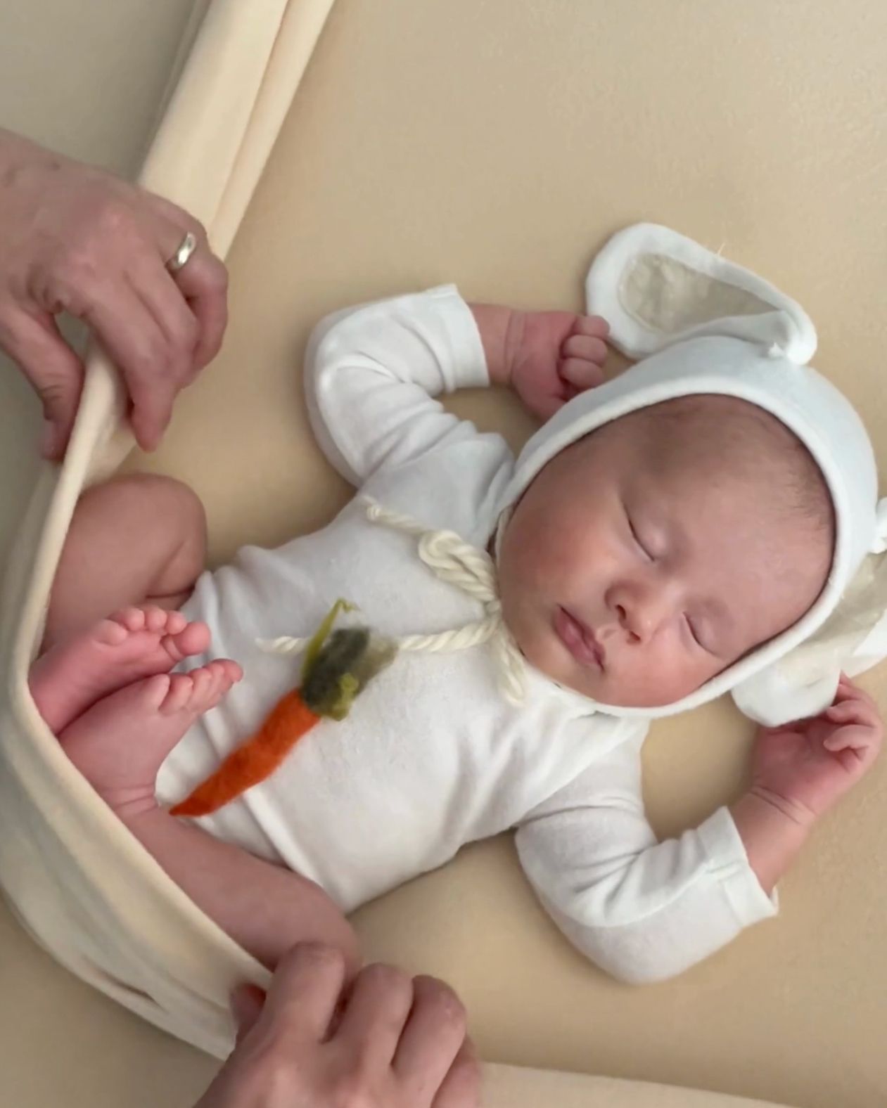 A sleeping newborn lies on white bedding wearing a white onesie and cap in a progression of photos.