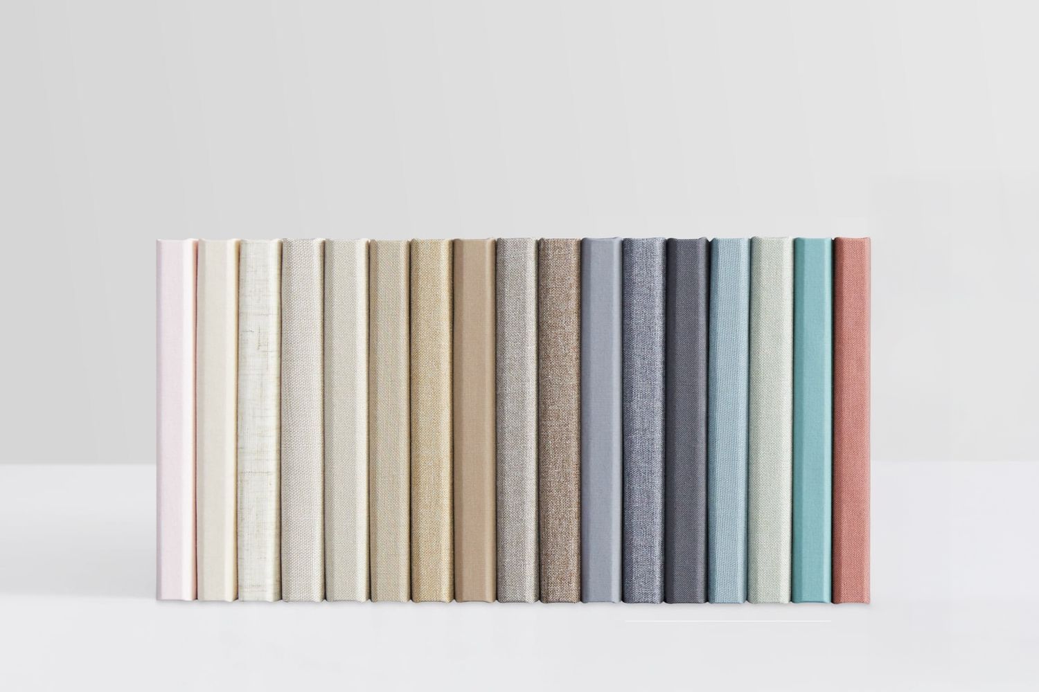 A row of books arranged in a minimalist gradient color sequence from white to mint green against a light gray background.
