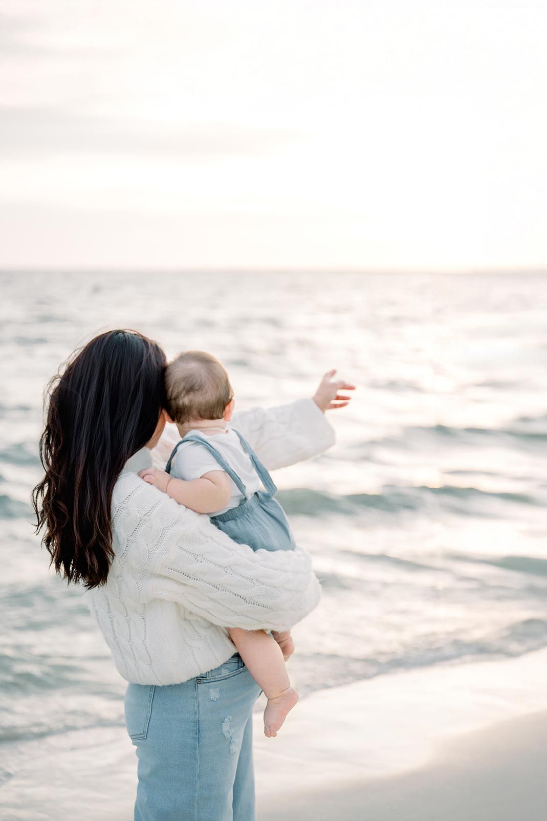 Intimate family embrace on a serene beach at sunset with rolling waves in the background.