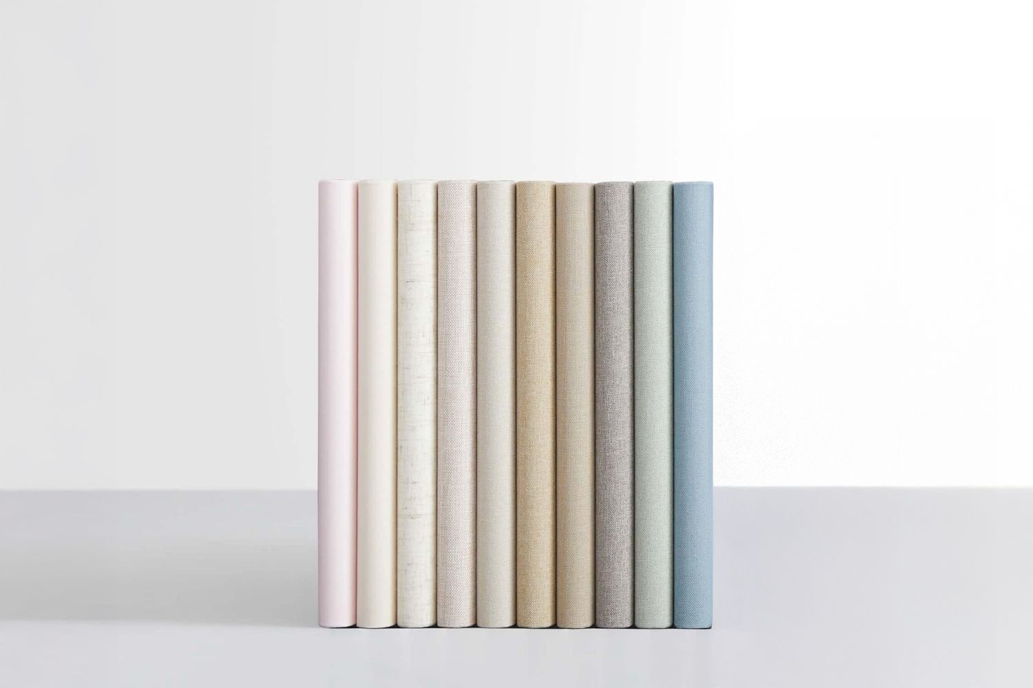 A minimalist display of pastel colored luxury hardcover books arranged in gradient order.