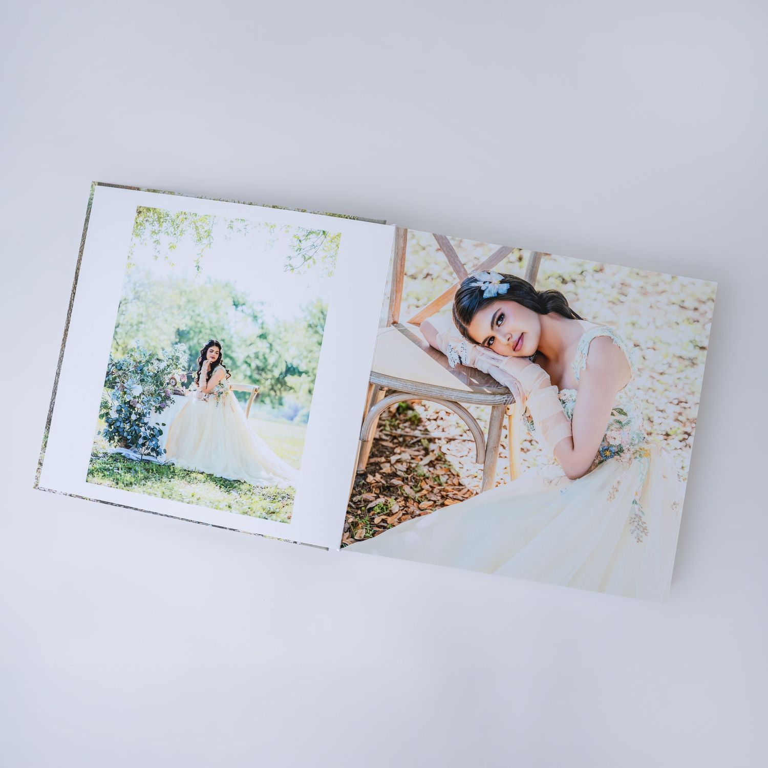 Open wedding photo album displaying two elegant bridal portraits of a woman in a white gown in a garden setting.
