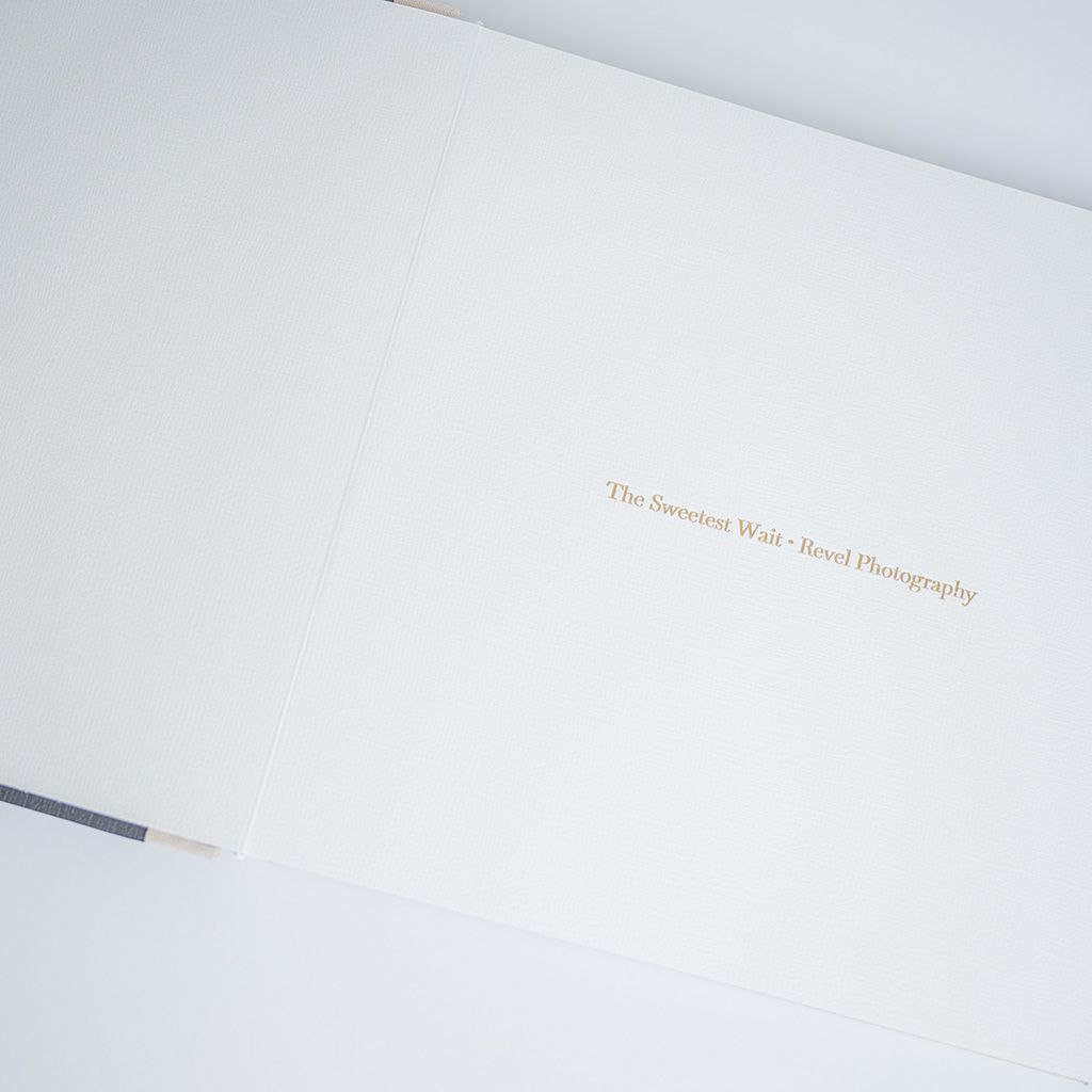 Open hardcover photography book titled The Innocent Wait - Breed Photography with gold foil text on cream cover.
