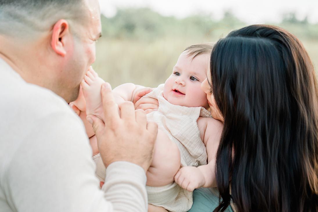 A precious outdoor family moment with a baby being gently held between two caring adults.