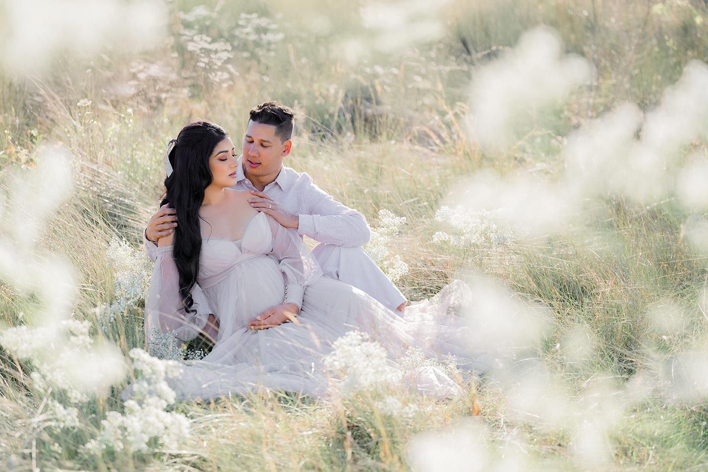 A romantic couple embraces in a dreamy sun-drenched field with soft bokeh lighting effects.