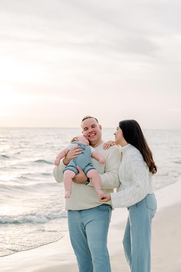 A family shares tender moments together on a peaceful beach at dusk.