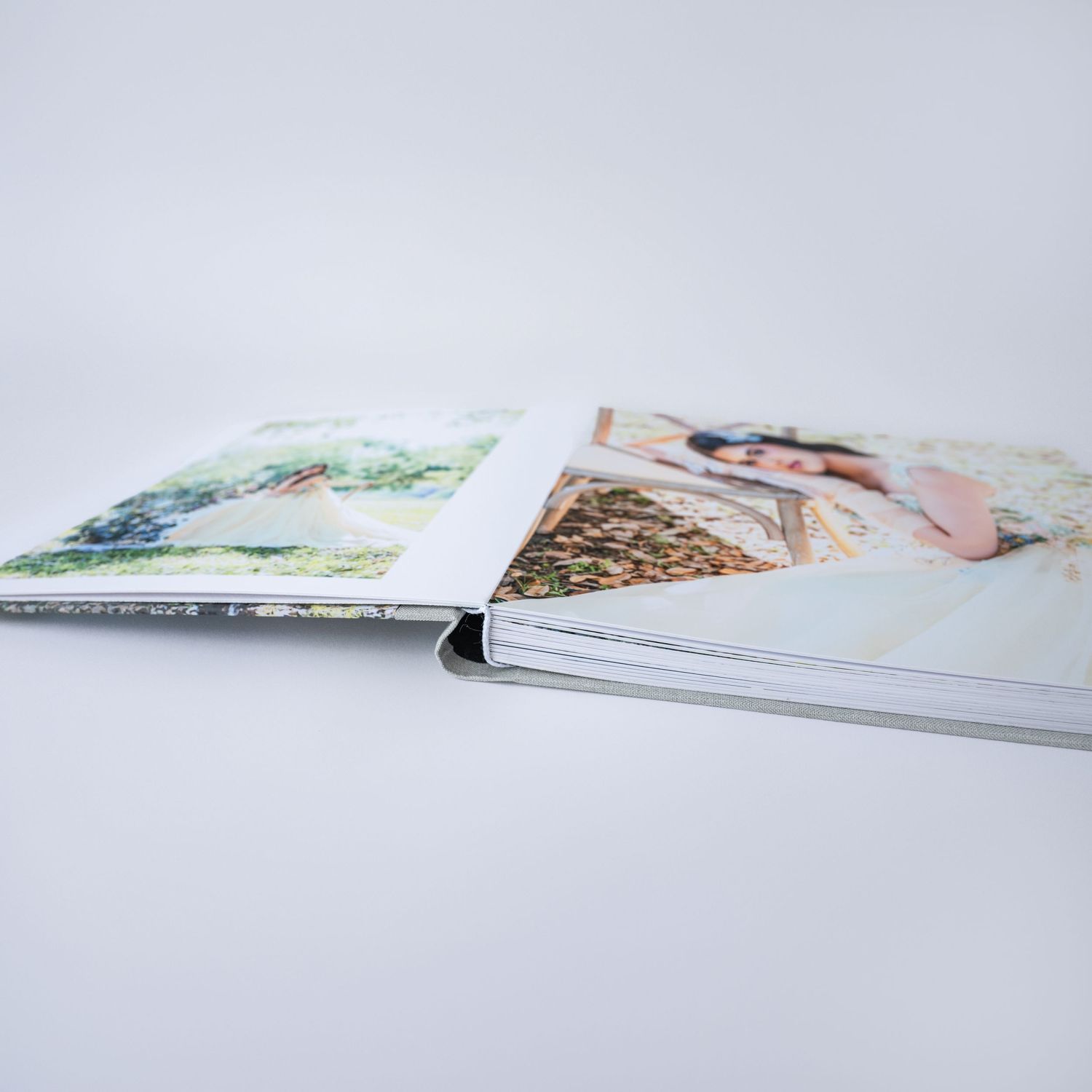 Open hardcover photo book displaying wedding photos with elegant watercolor imagery on white background.