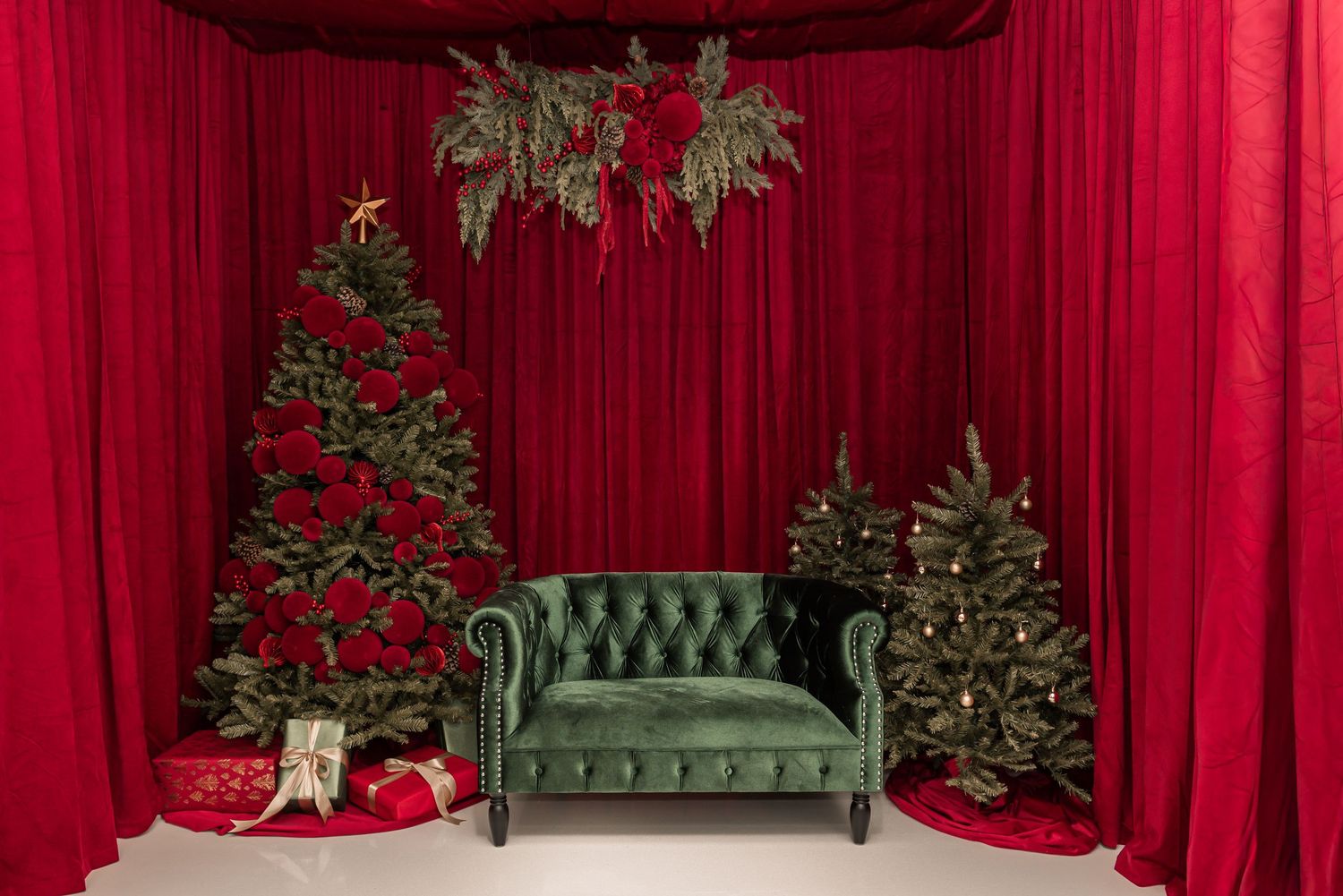 Red velvet theater curtains with holiday greenery and decorative elements create an elegant Christmas backdrop.