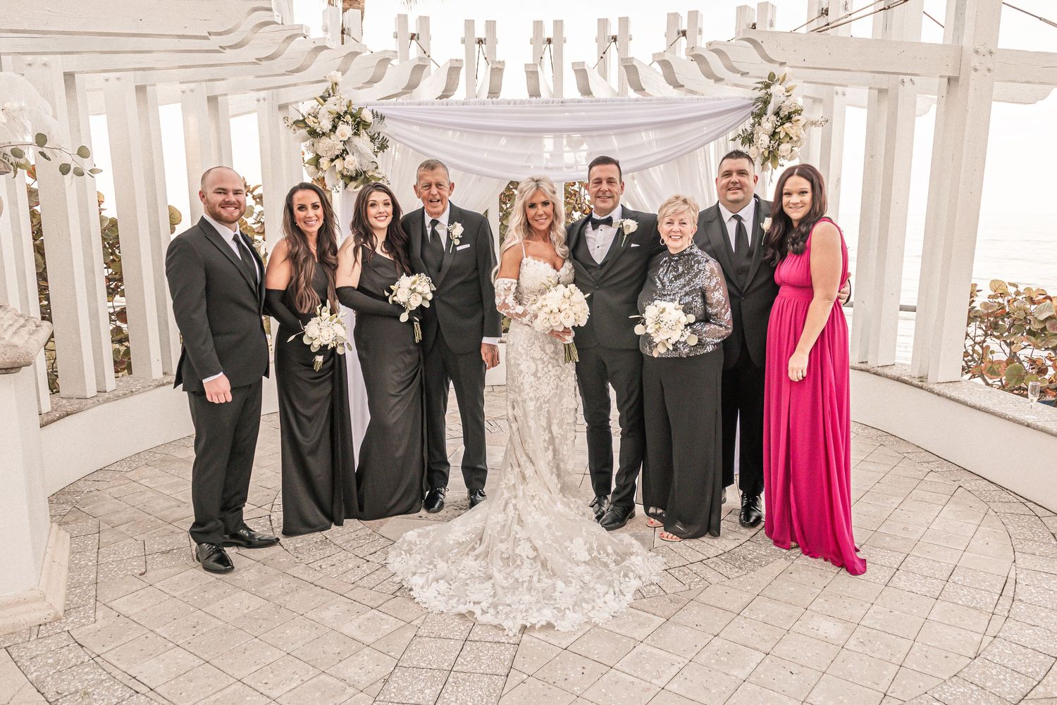 Wedding party poses together in an elegant white rotunda with ornate architectural details and decorative columns.