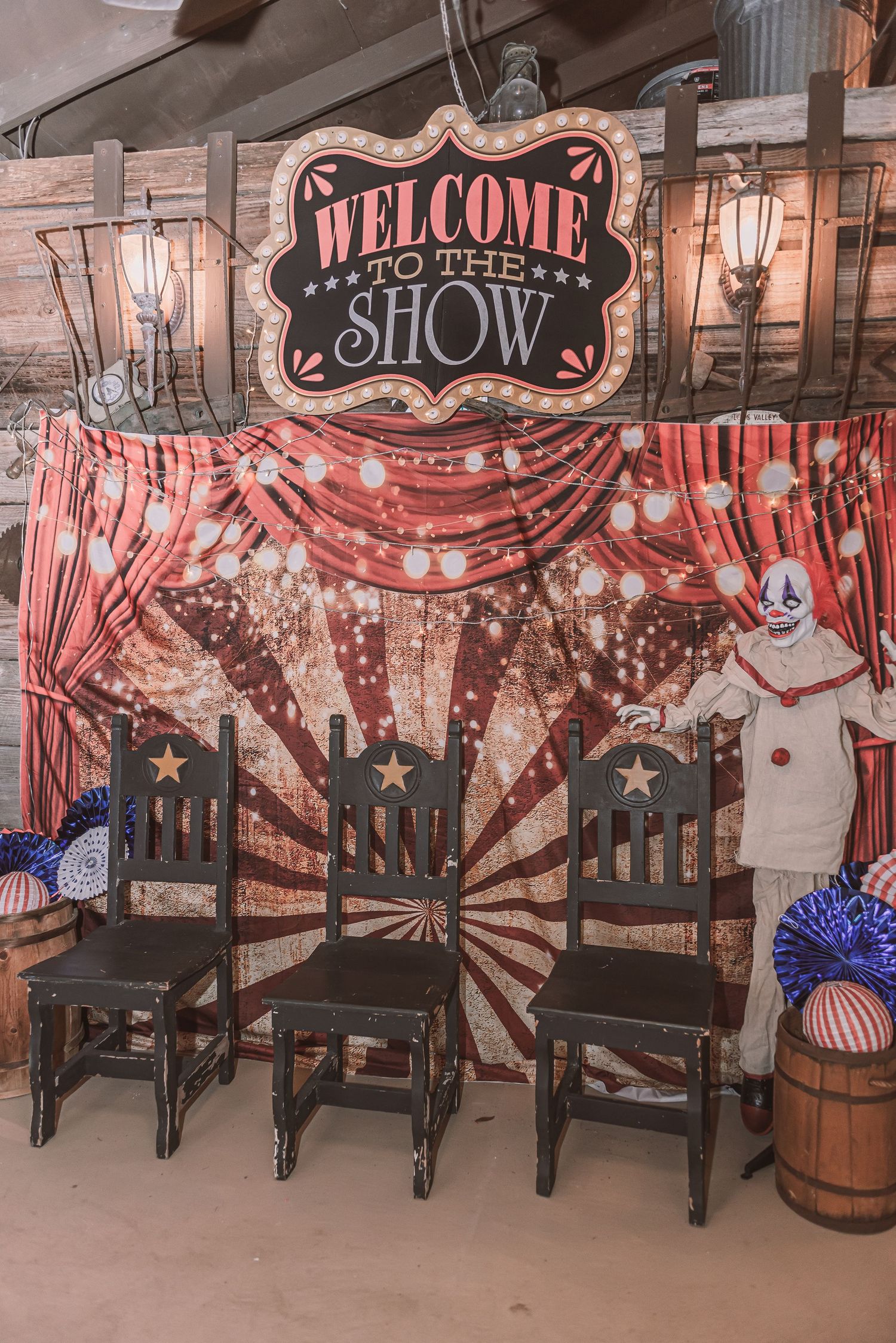 A vintage circus-themed display with 'Welcome to the Show' sign, black chairs and red striped backdrop with carnival decor.
