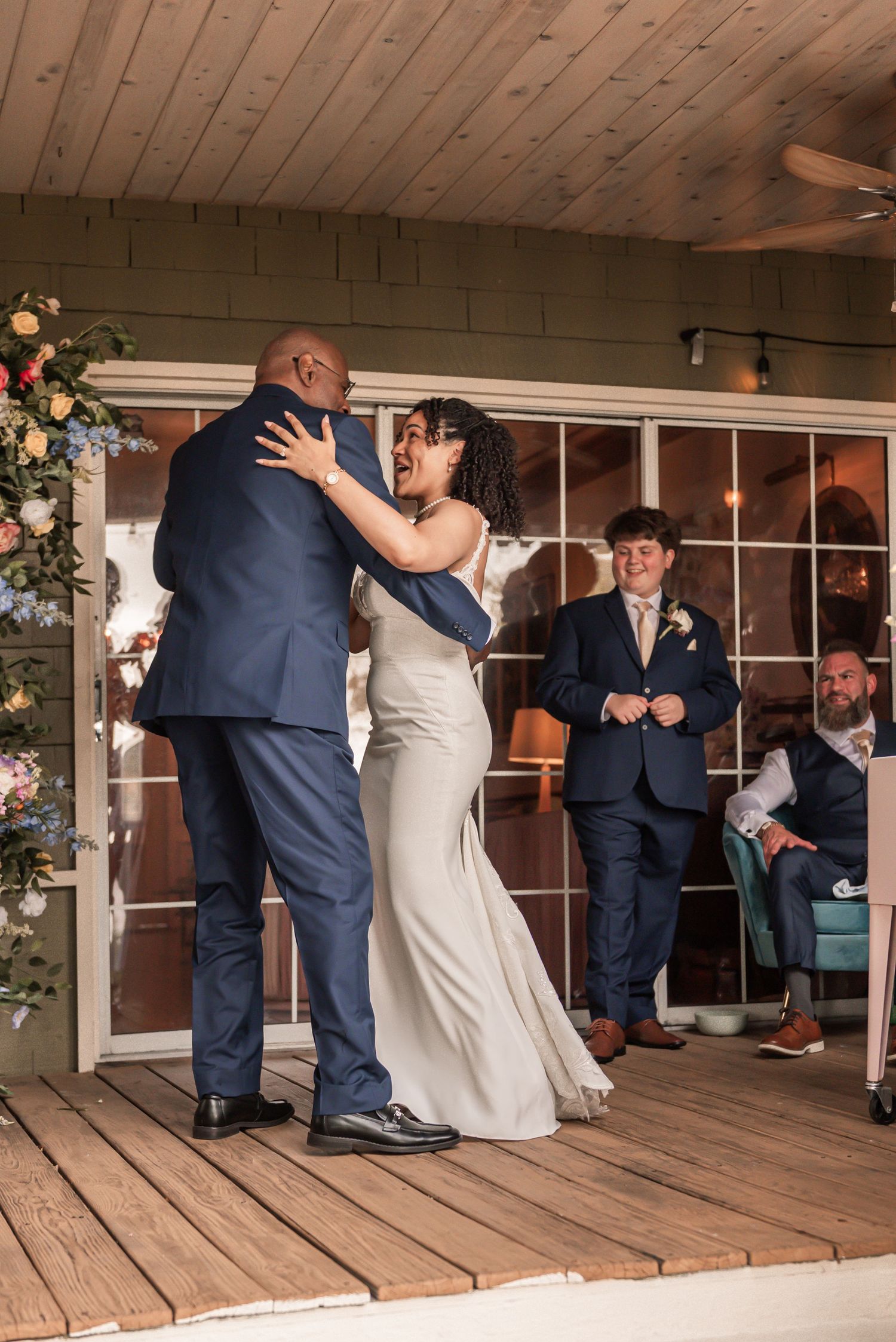 Bride and groom share their first dance at an indoor wedding reception while guests watch in the background.