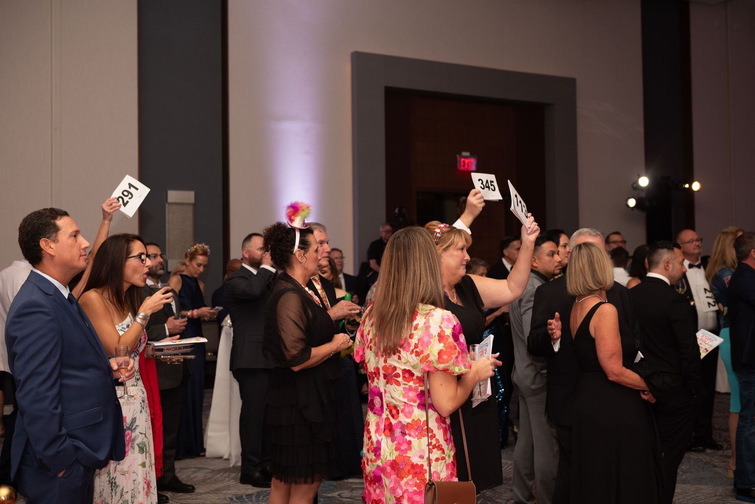 Wedding guests on a dance floor enjoying themselves at a reception with purple accent lighting in the background.