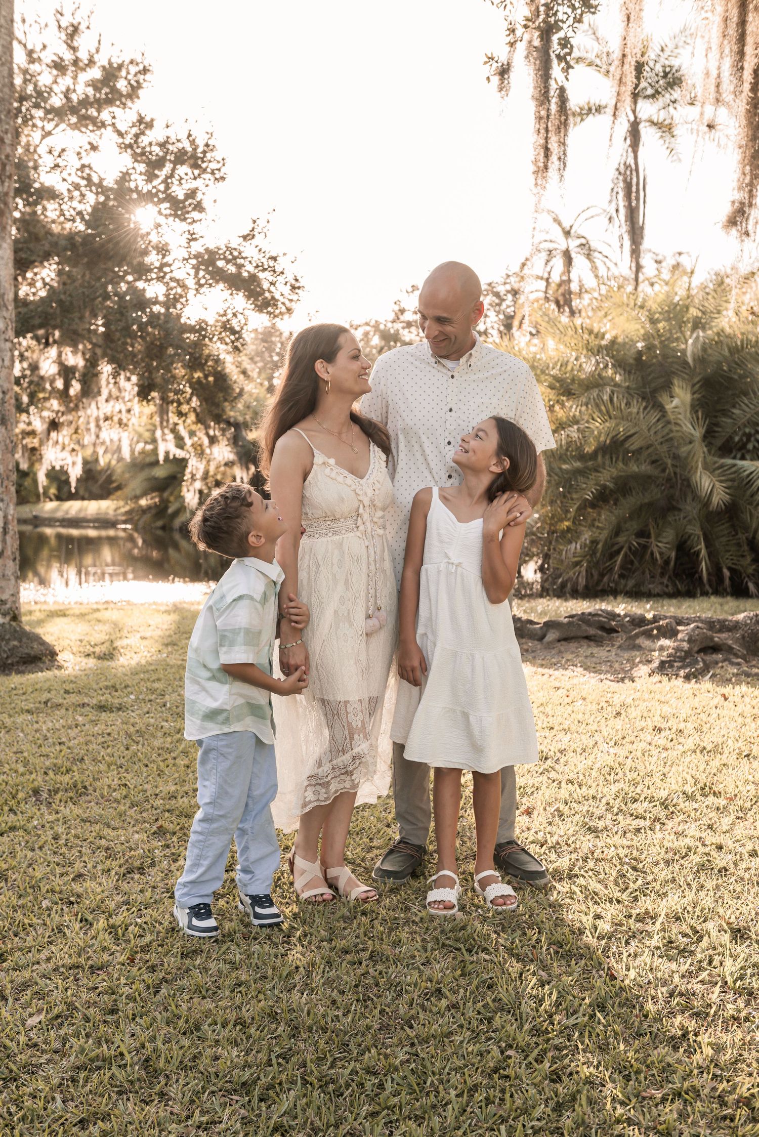 Children playing and laughing together on a grassy hill during golden hour at sunset.