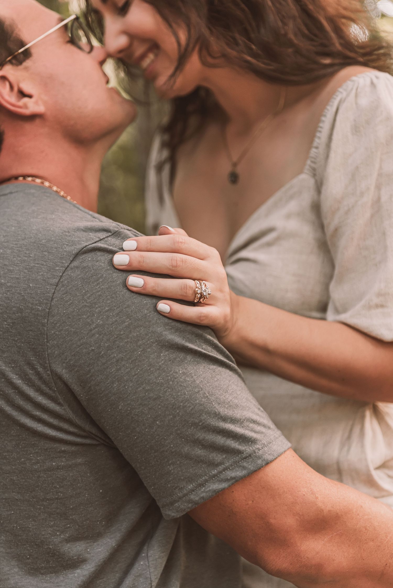 Close-up of couple embracing with engagement ring visible on hand.