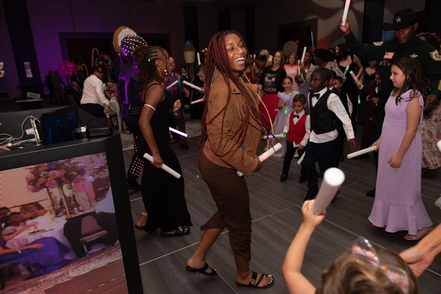 People dancing together at an indoor event with purple lighting and formal attire.