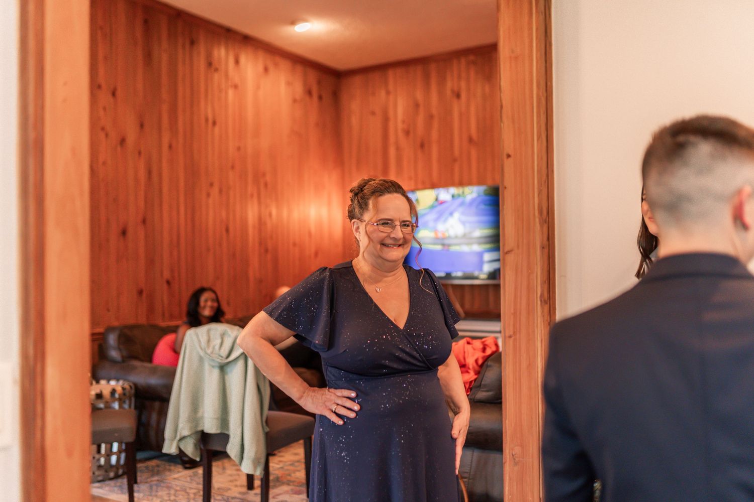 People gather in a wood-paneled room for a social event with drinks and conversation.