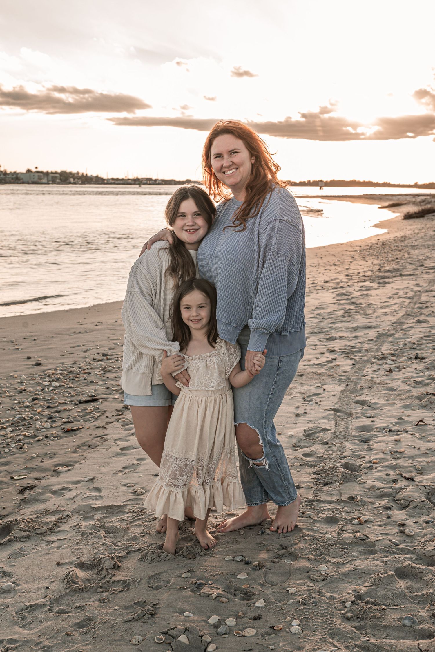 Family enjoying a sunset moment together on a sandy beach with warm golden light and ocean views.