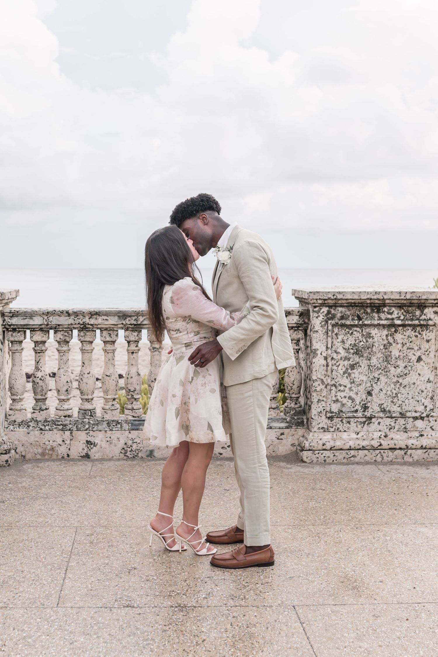 A series of proposal photos showing a couple embracing on a stone terrace against a cloudy sky.