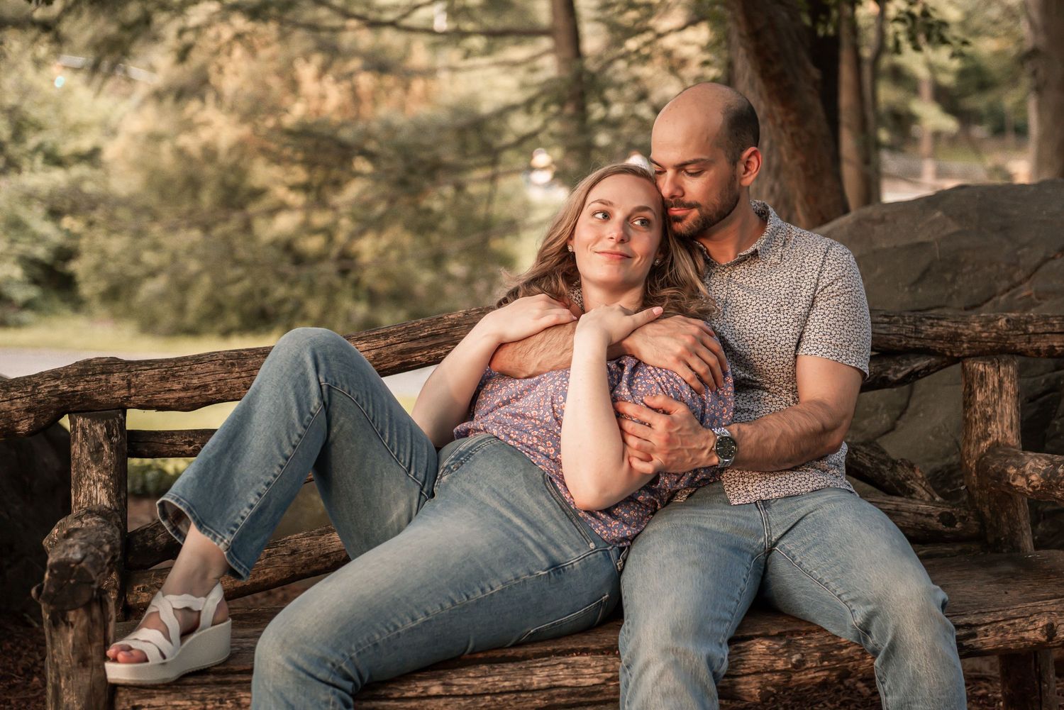 Couple in comfortable casual wear rests sweetly on timber logs in a rustic nature setting during golden hour.