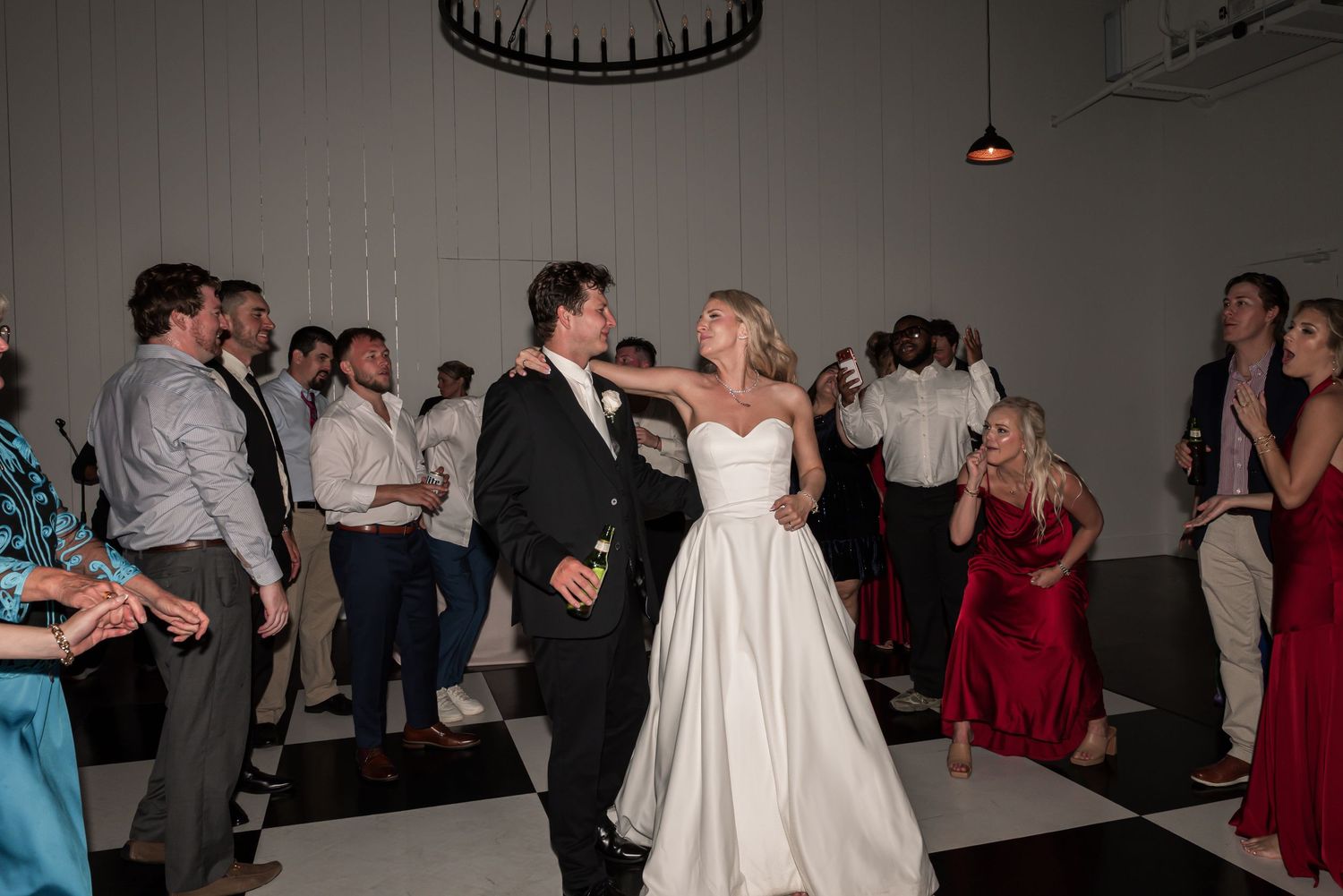 Bride and groom share first dance surrounded by guests at elegant wedding reception venue.
