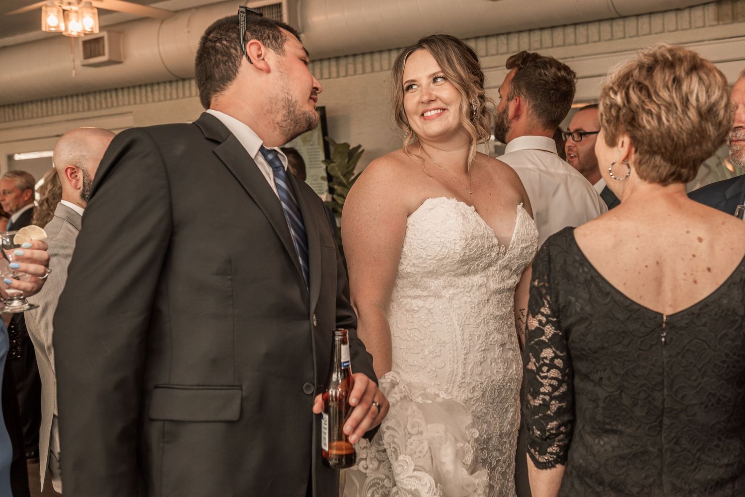 People enjoying themselves at a wedding reception with guests dressed in formal attire including a white gown and black suit.