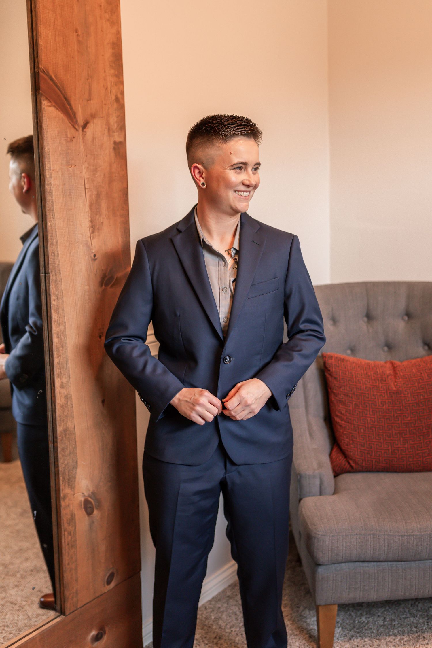 A series of photos showing a person adjusting and wearing a navy blue suit while standing near a gray couch.