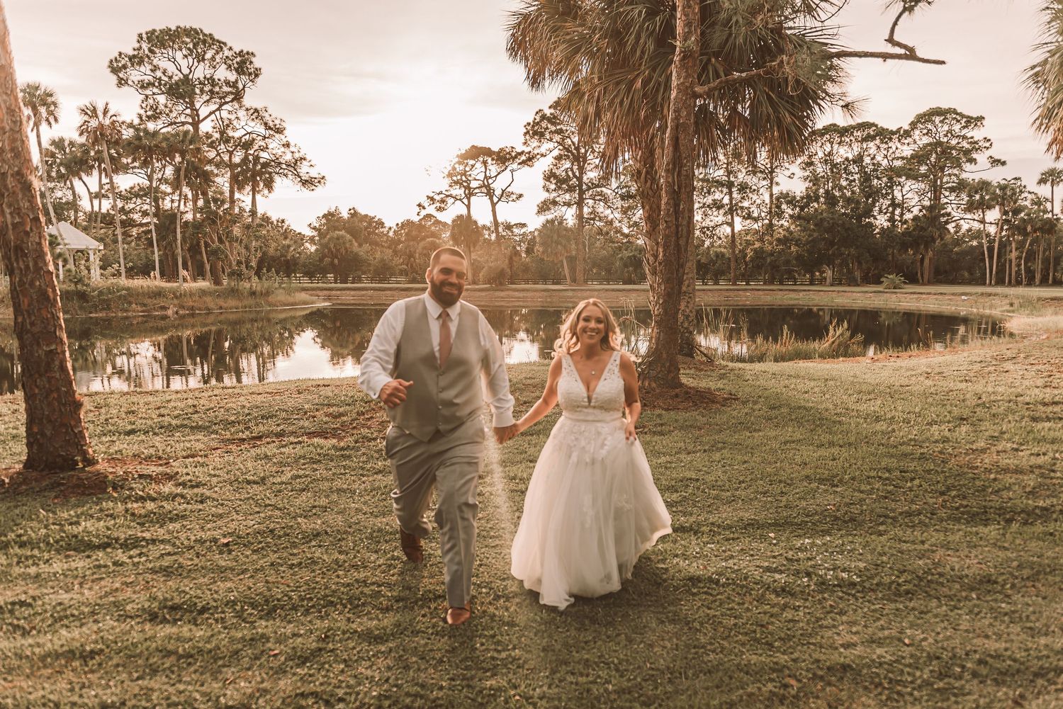 A couple walks hand in hand through a sun-drenched field at golden hour creating a romantic silhouette against the landscape.