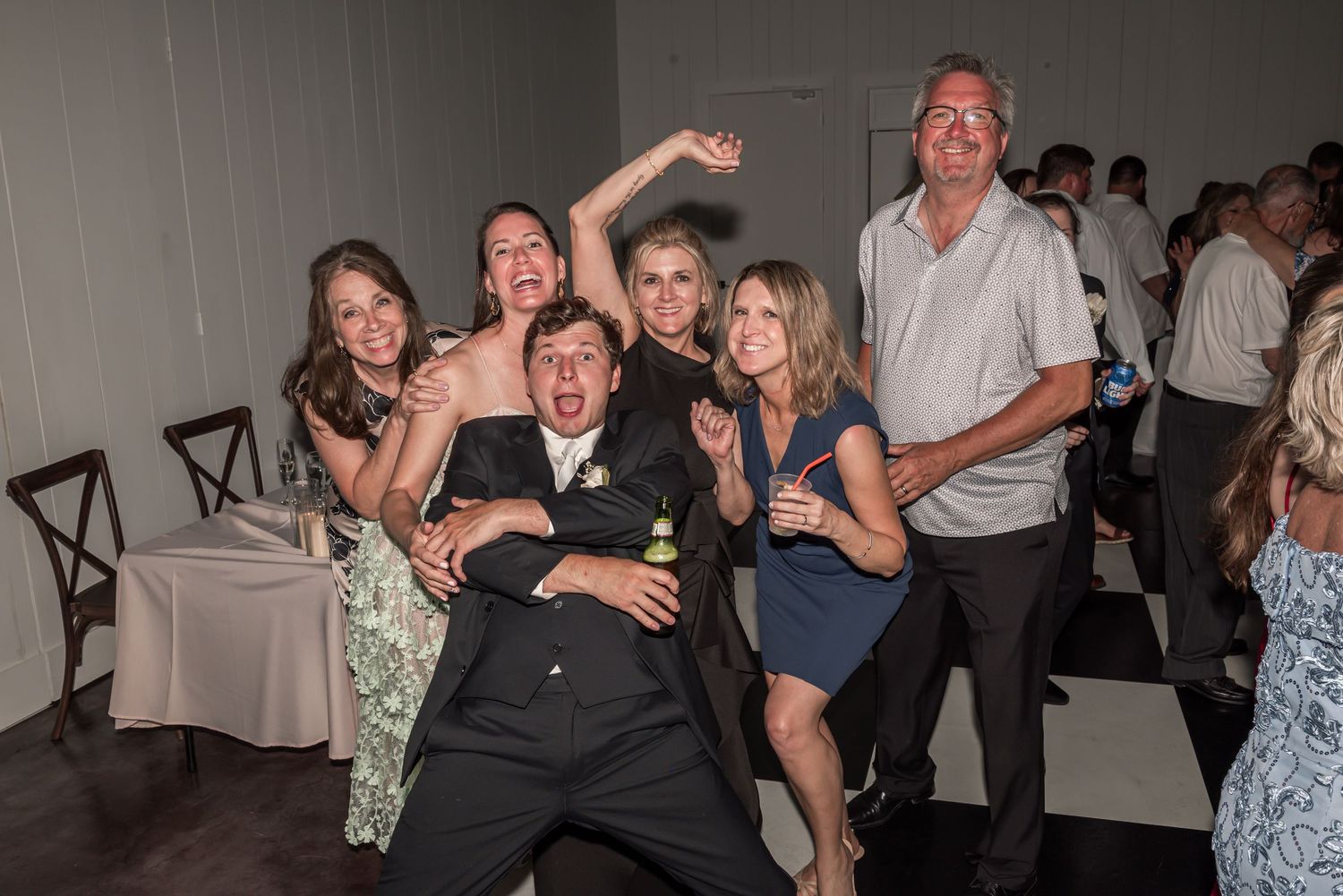 Group of friends celebrating at a wedding reception, dancing and posing joyfully on the dance floor.