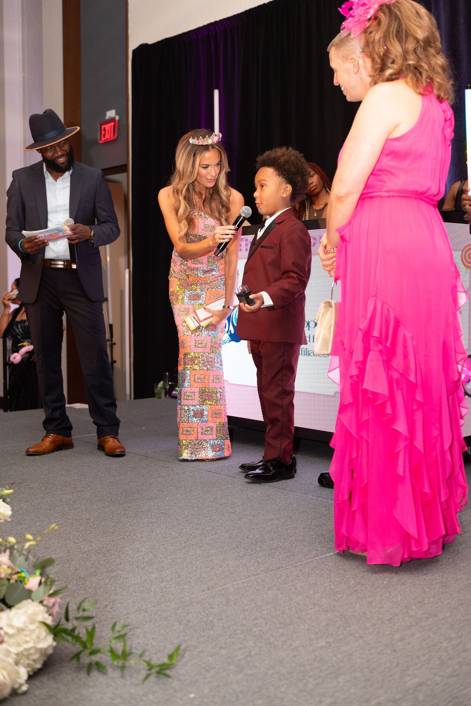 Wedding guests in pink dresses and formal attire gather in a hallway during a reception celebration.