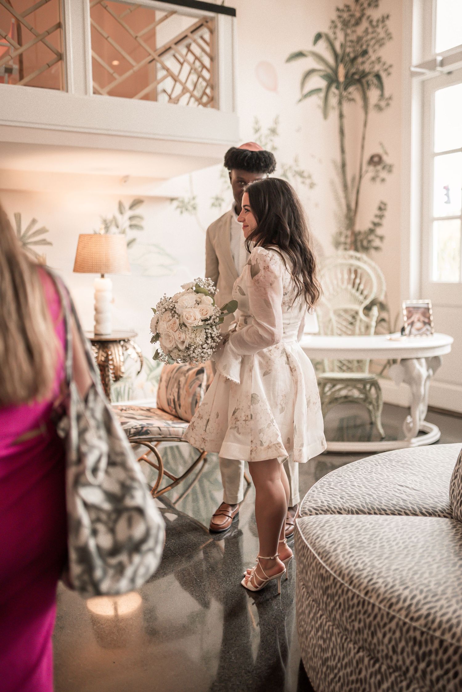 A series of connected photos showing a young child in a white dress playing and jumping on a bed with floral wallpaper.