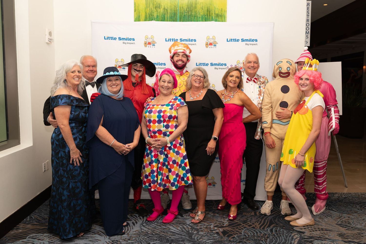 A group poses together at a charity event wearing colorful formal attire and smiling for photos.