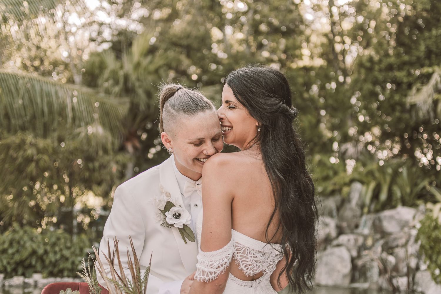 Intimate wedding moment captured between couple in tropical garden setting.