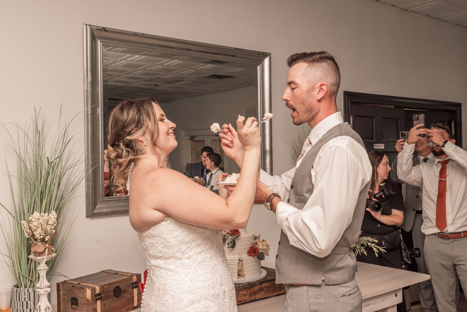 A couple shares a playful moment while cutting their wedding cake at their reception celebration.