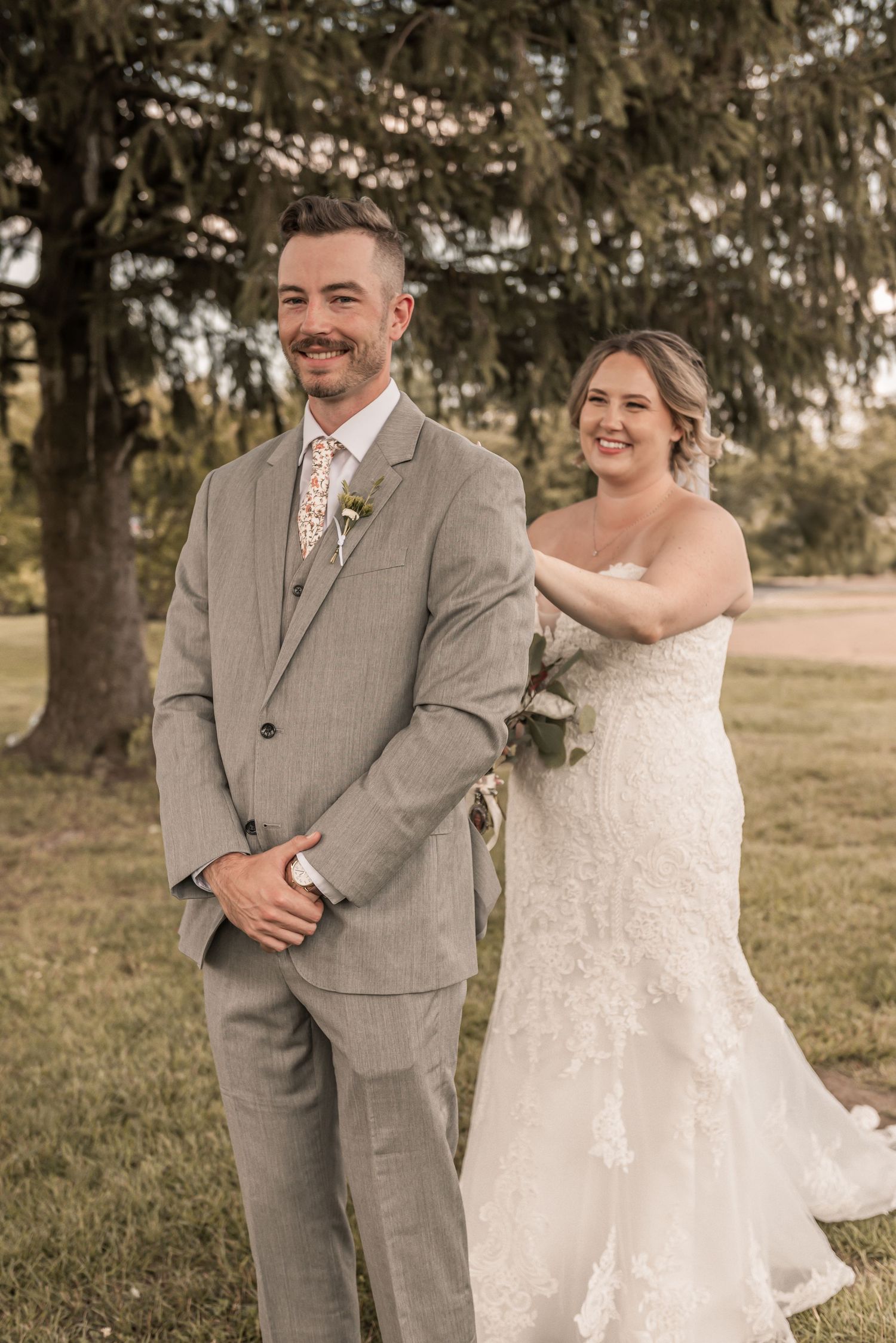Candid sequence captures sweet first-look moment between newlyweds outdoors under a large tree.