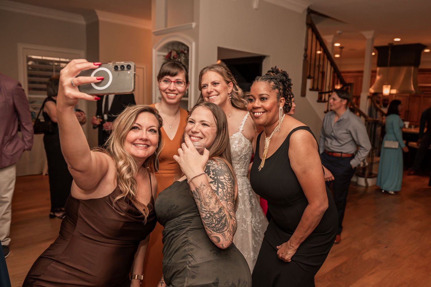 A group of friends taking a selfie together at a party in a warmly lit indoor venue.