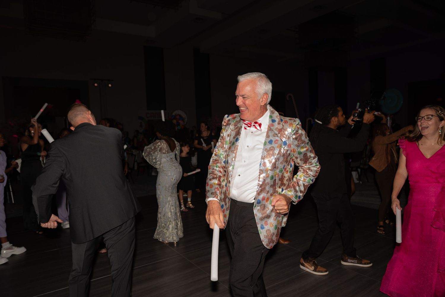 People dancing and socializing at a dimly lit evening party or reception venue.