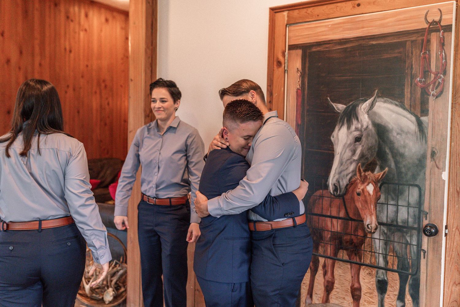 A sequence of people in blue and white attire working with horses in a rustic wooden barn setting.