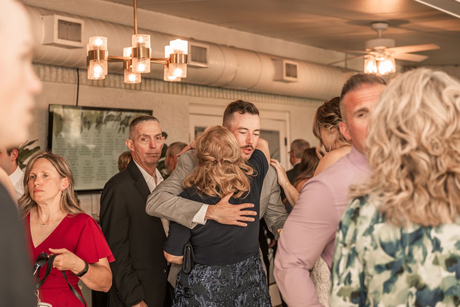 People gathered at an indoor social event with warm lighting and celebratory atmosphere.