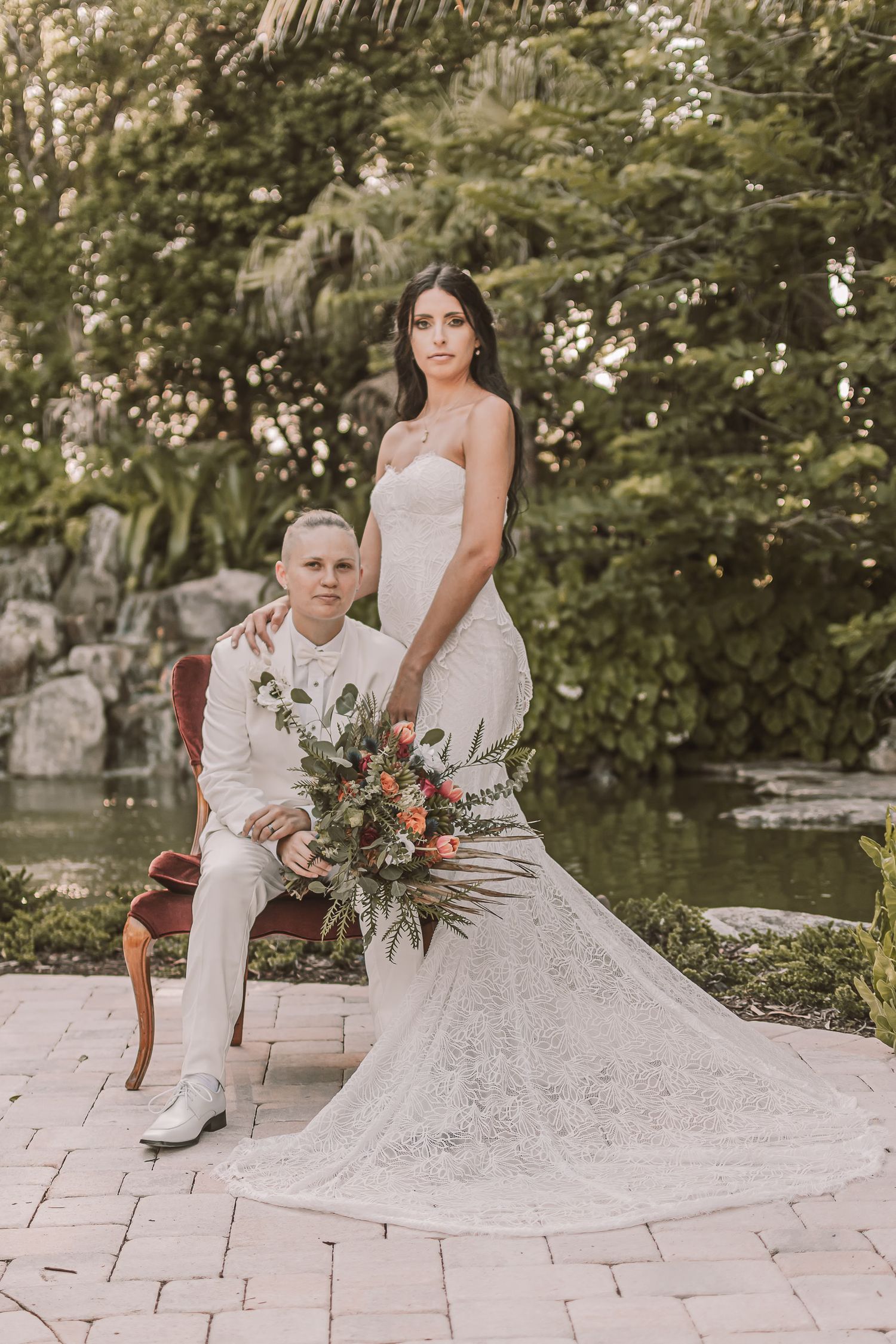 A romantic outdoor wedding photo session with a couple on stone pavers surrounded by lush greenery and florals.