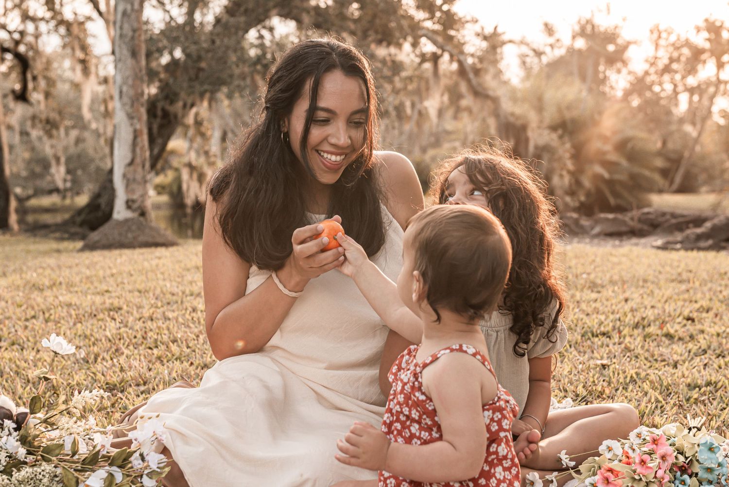 Two people sharing a joyful moment while sitting on grass during golden hour sunset in a park setting.