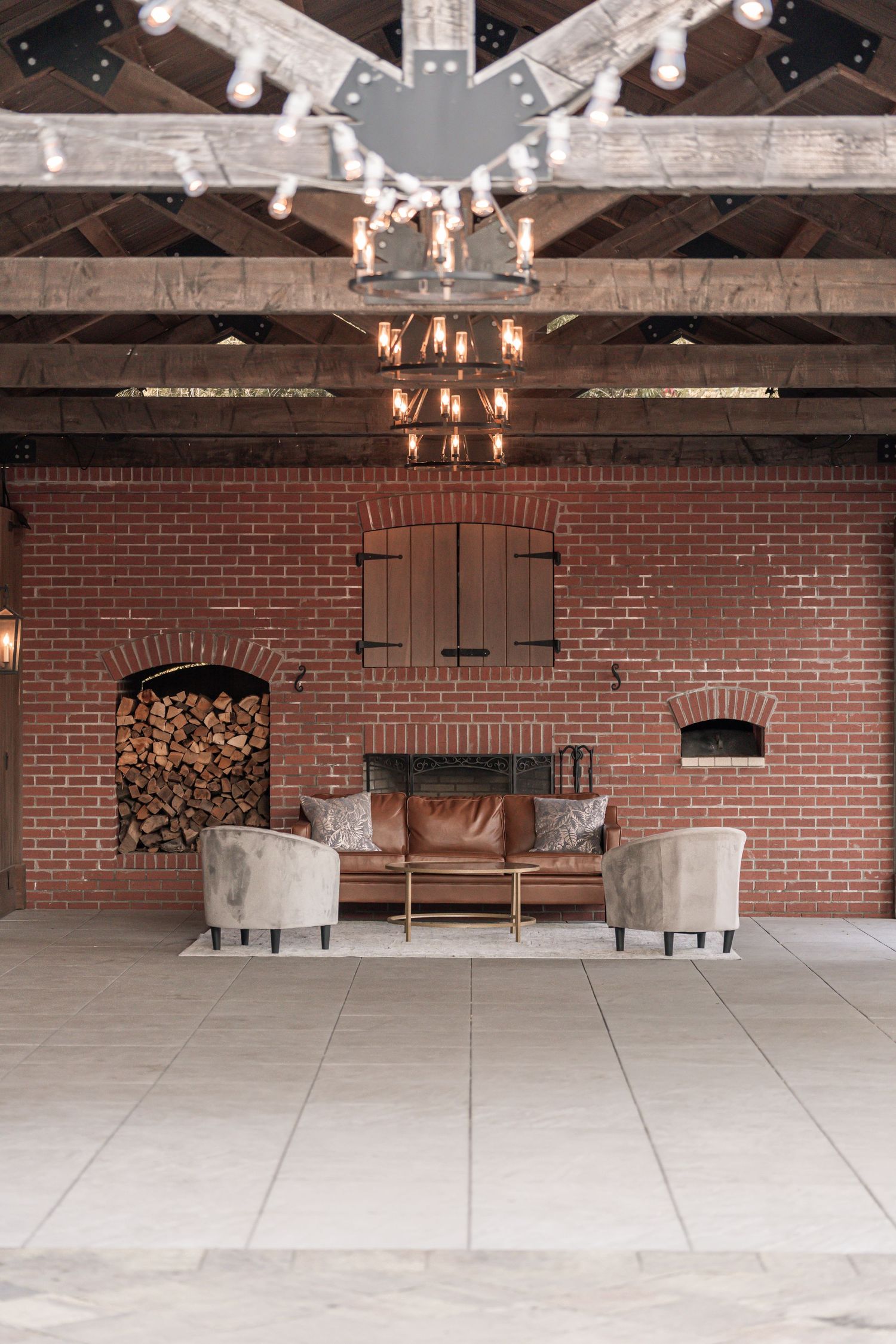 Rustic event venue interior with exposed brick walls, concrete floors, and vintage chandeliers in an industrial space.