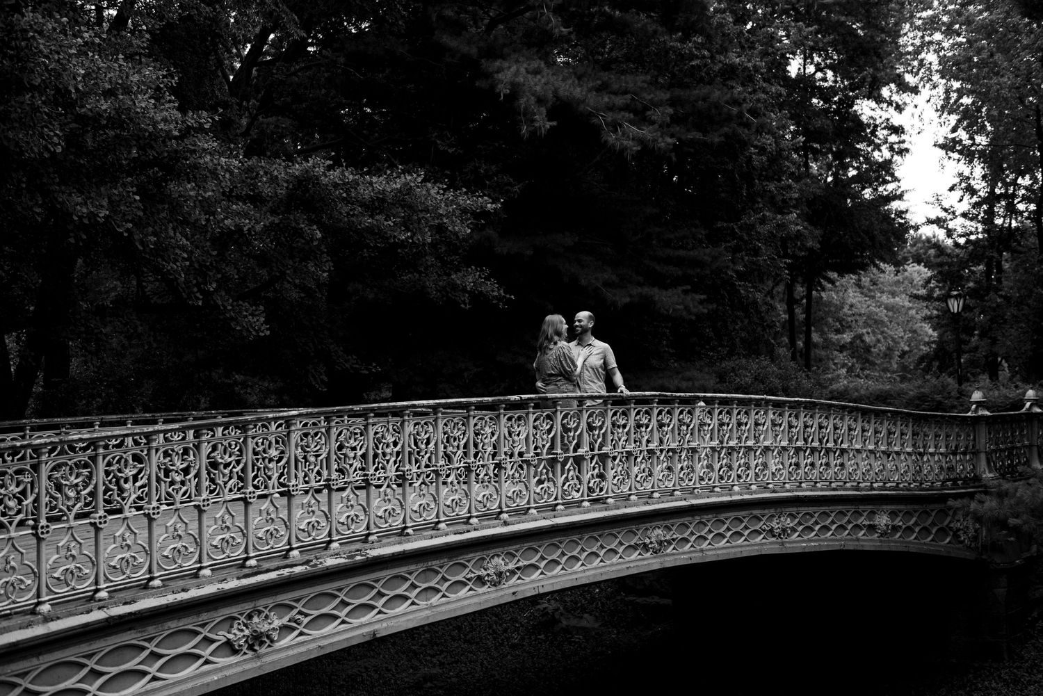 A black and white panoramic view of Central Park's historic Oak Bridge with decorative iron railings spread across images.