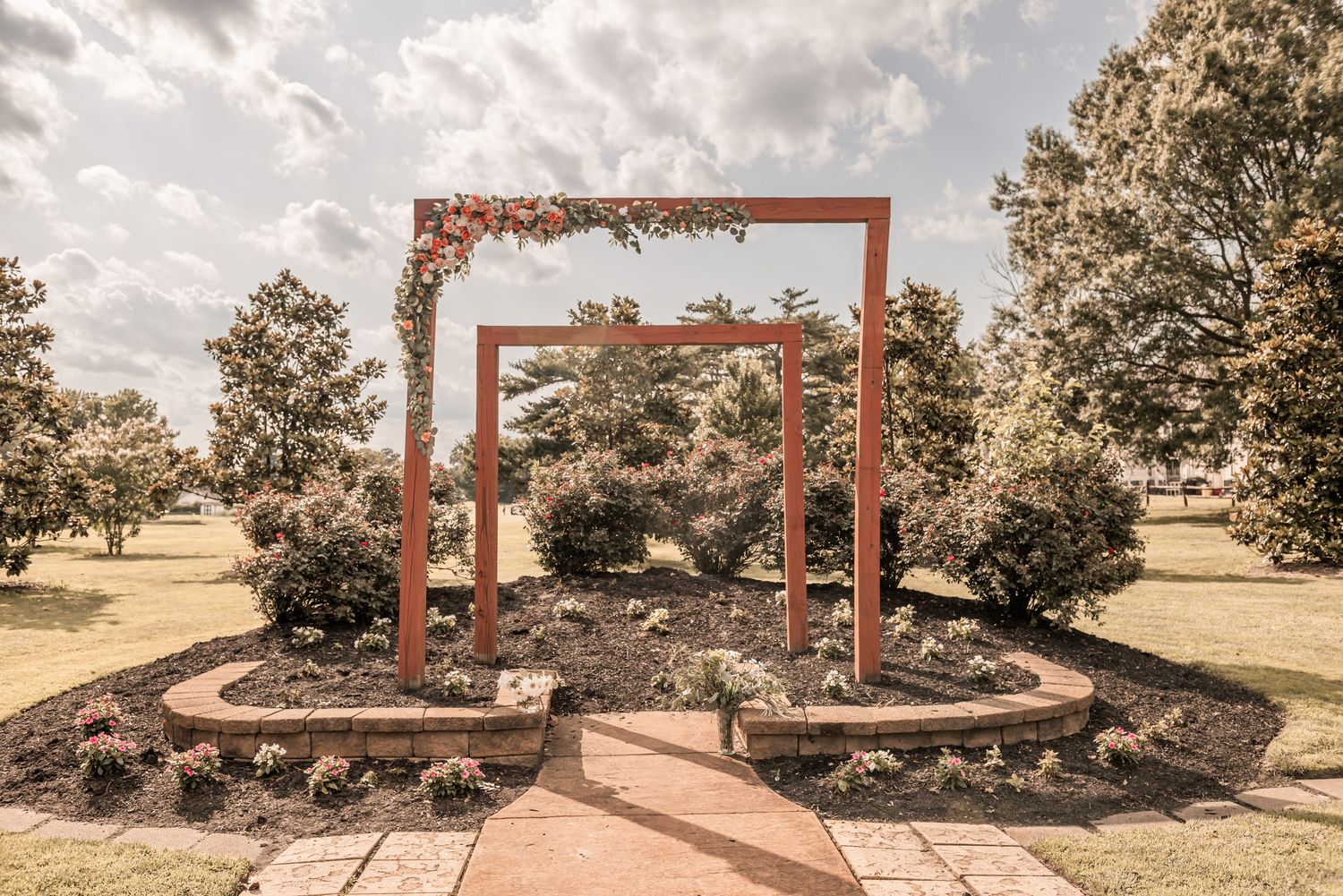 Curved garden path leads through rustic wooden archways surrounded by native landscape plantings and drought-resistant vegetation.