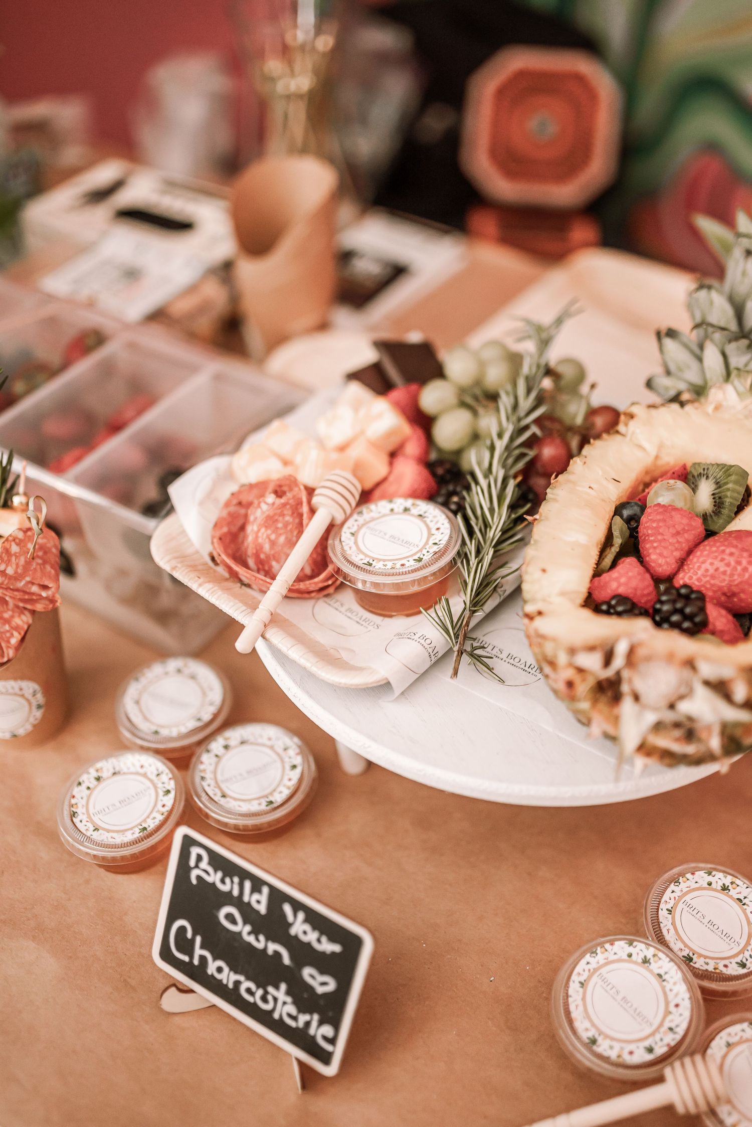 Elegant dessert table display with fresh berries, charcuterie, and rustic French-style signage on a cream tablecloth.