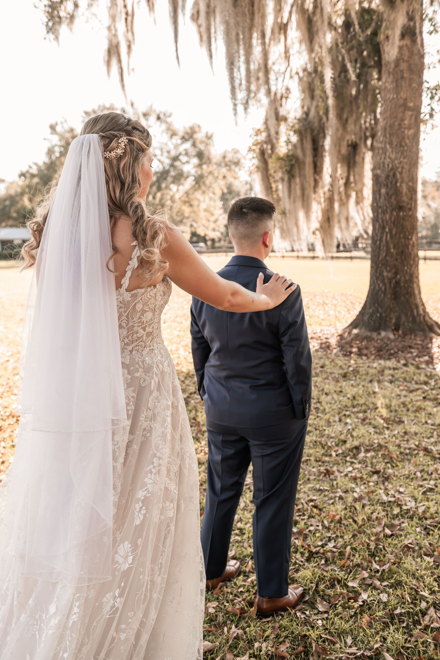 A romantic wedding photo series showing a couple walking among Spanish moss draped trees at sunset.