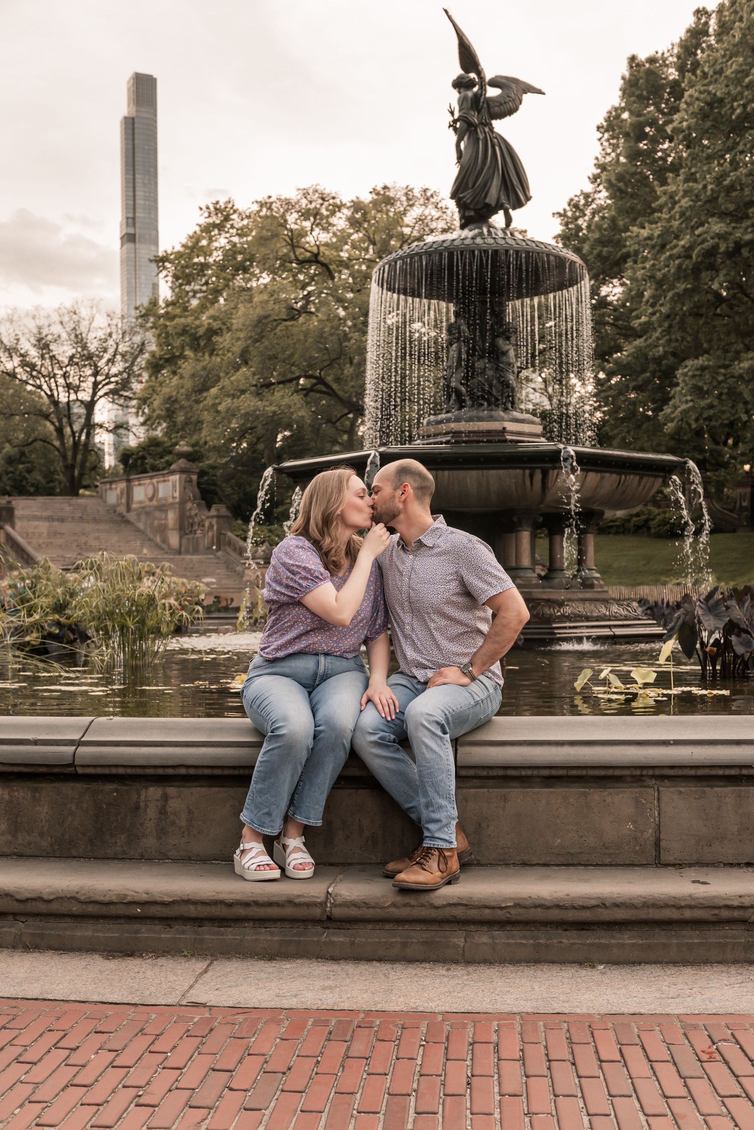 Romantic couple sitting on fountain ledge in park during autumn sharing sweet moments together.