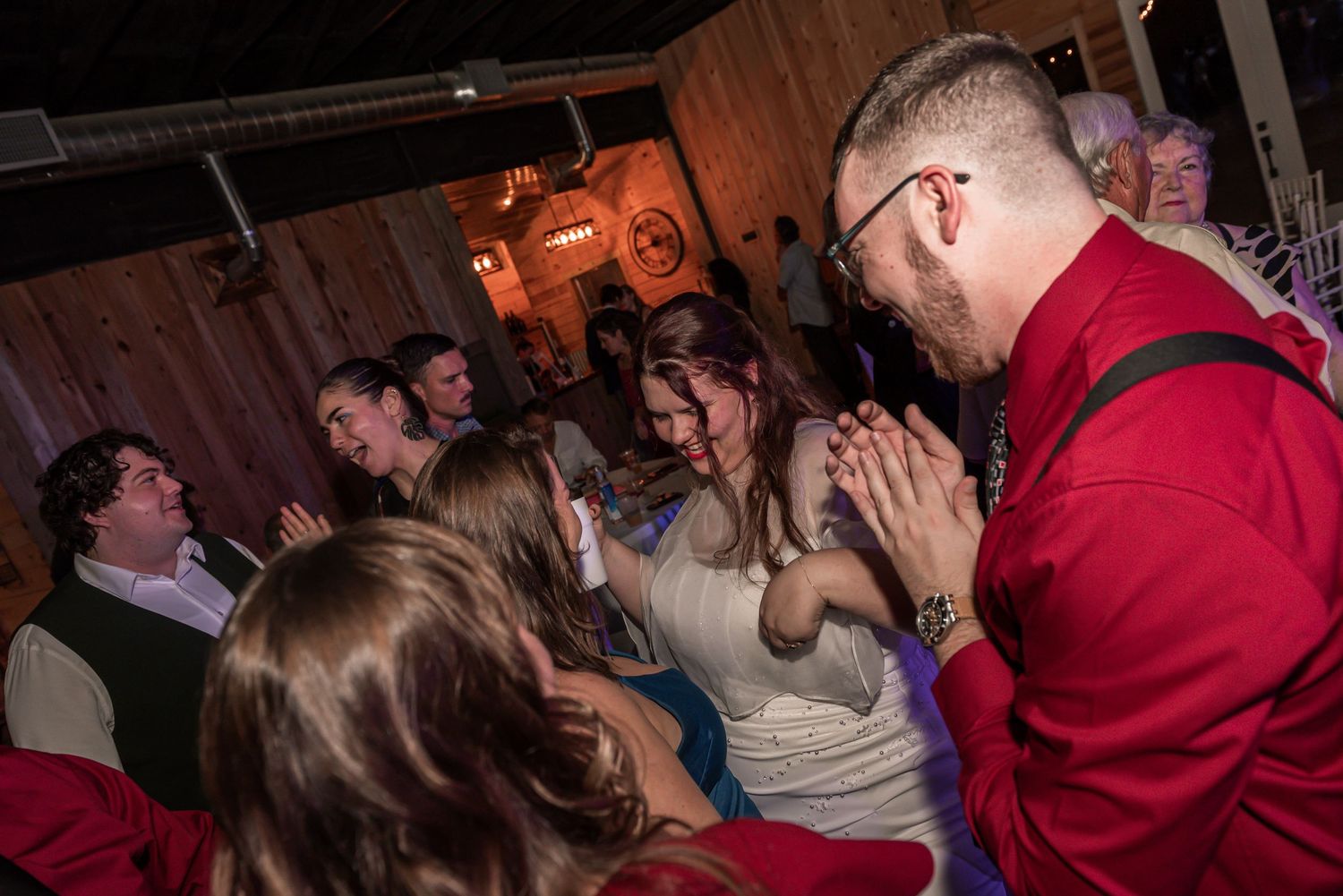 Crowd of people dancing and socializing at a dimly lit nightclub with red lighting.
