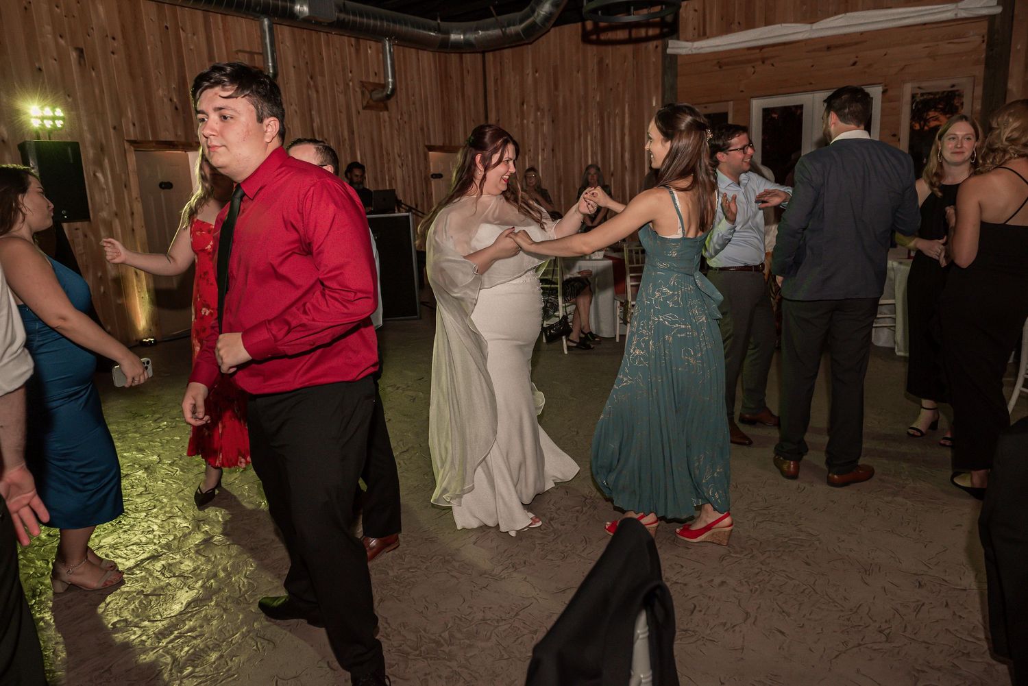 People dancing together in a rustic barn setting during a wedding celebration.