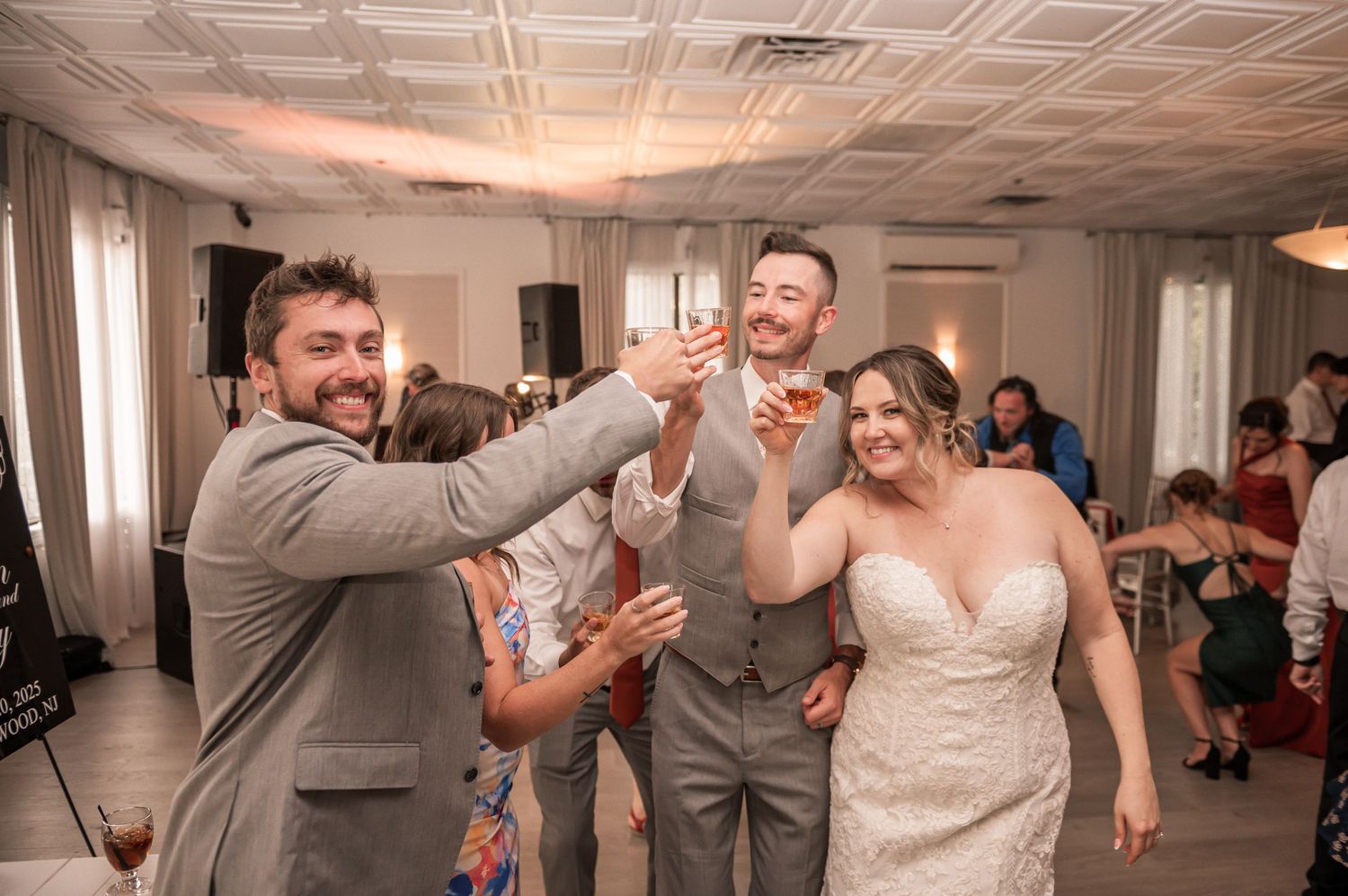Wedding guests celebrate with a toast at a reception in an indoor venue.